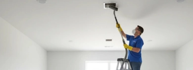 Professional cleaners using long-hose vacuums on a ladder to perform thorough air vent and duct cleaning in a newly renovated room.