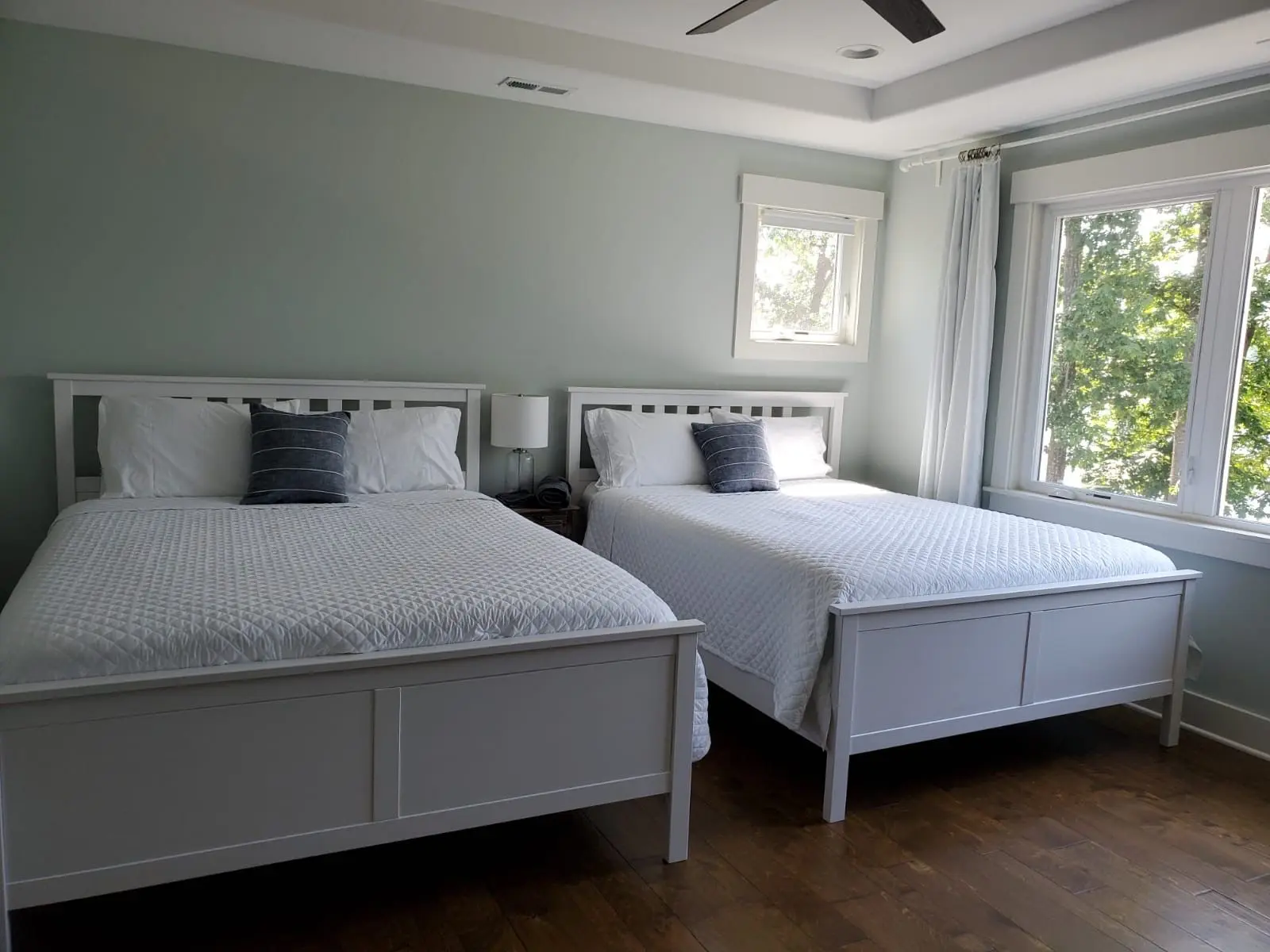 A bright and inviting guest bedroom with two beds, showcasing the expert Airbnb cleaning service by Brighthouse Cleaners.