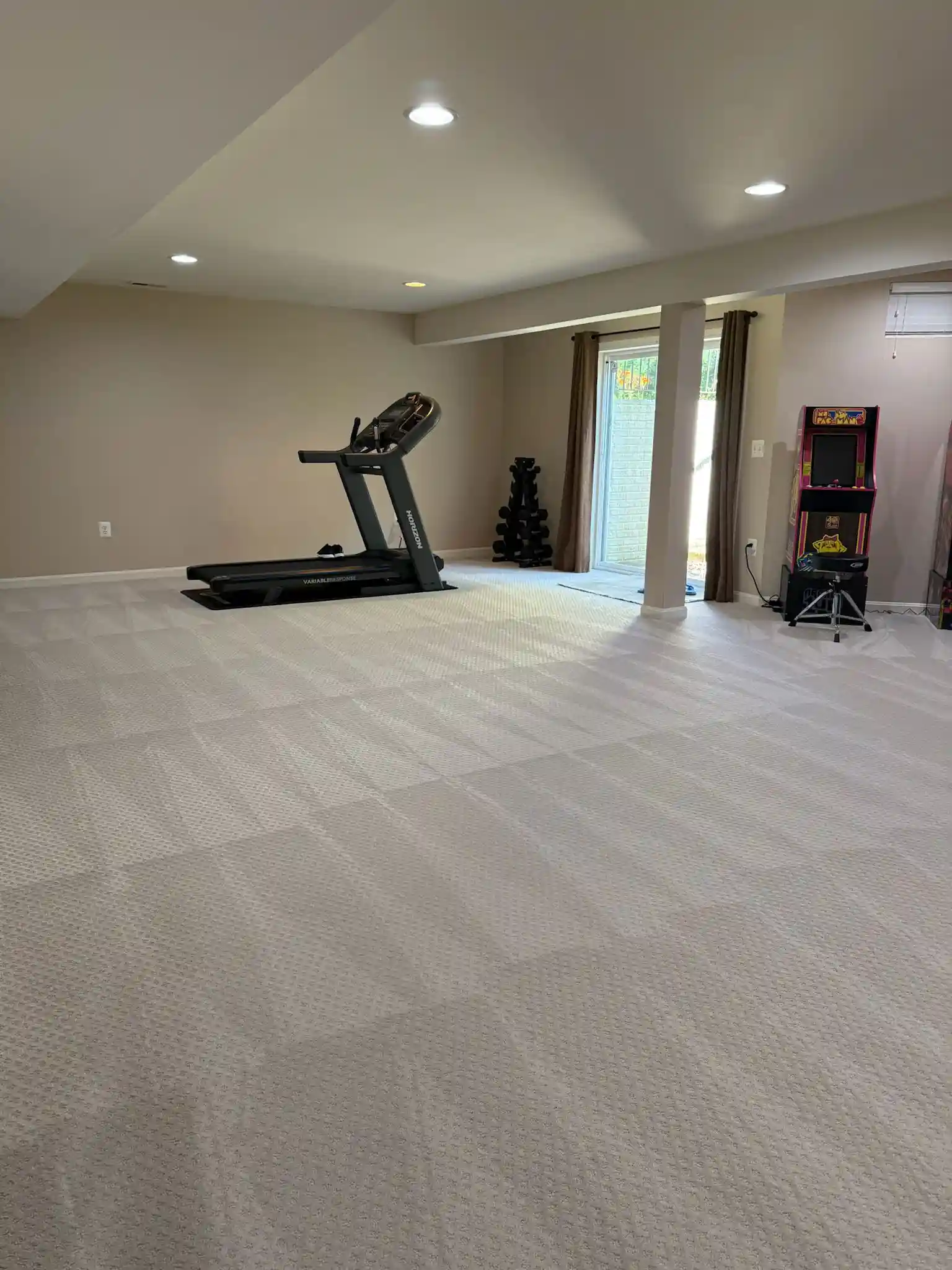 A spacious home gym with a treadmill and weights, kept spotless by Brighthouse Cleaners home gym cleaning service.
