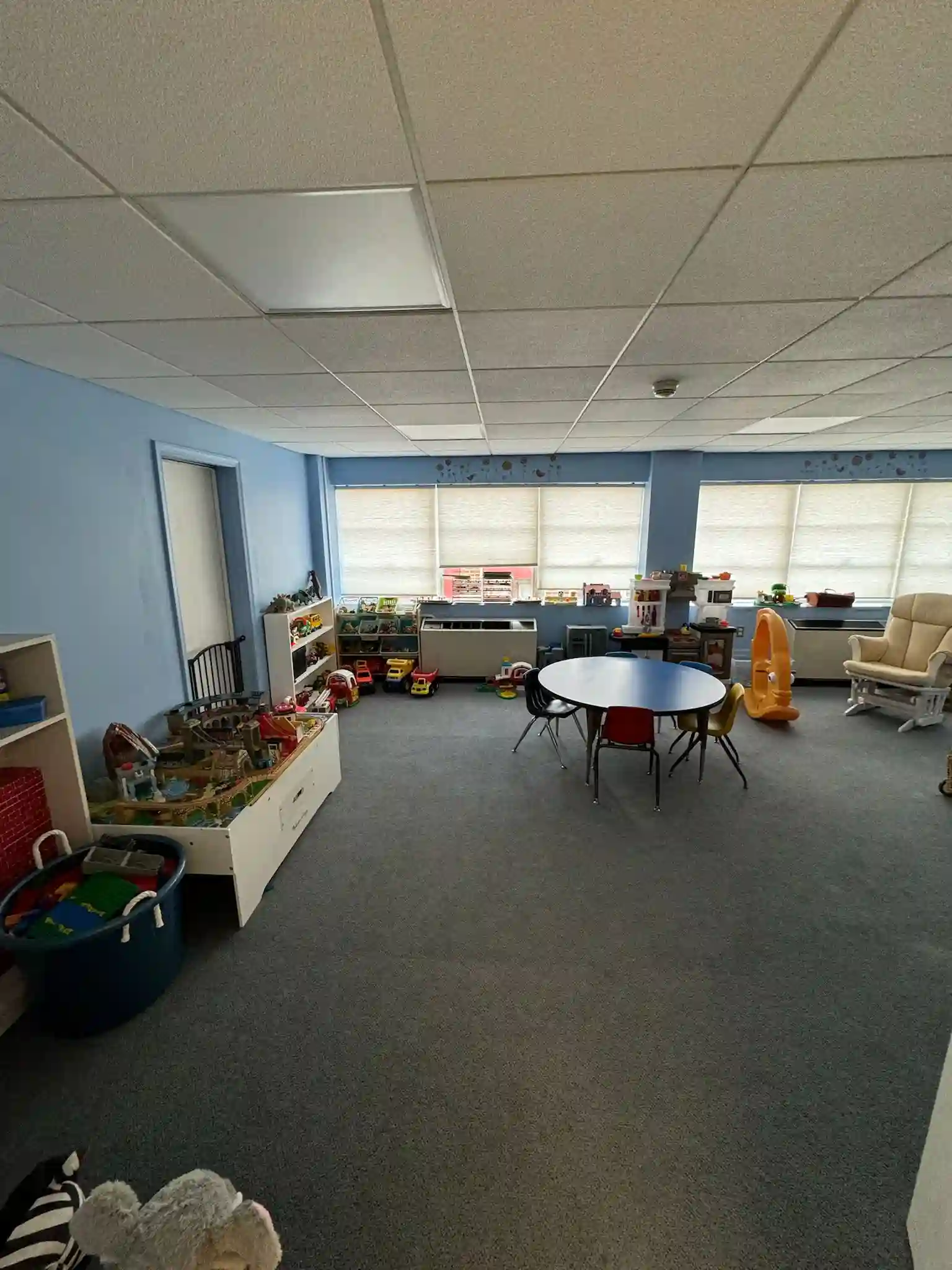 A tidy playroom with toys, a children's table, and blue walls, maintained by Brighthouse Cleaners for playrooms cleaning service.