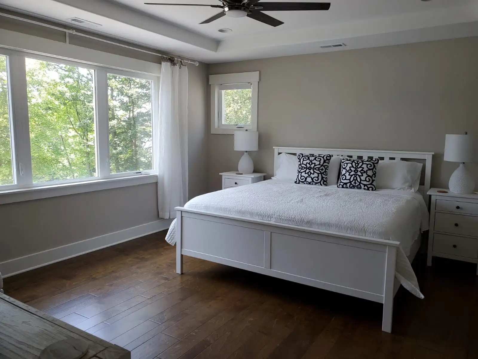 A bright, spotless bedroom with a white bed and hardwood floors, cleaned by the professional bedroom cleaning service of Brighthouse Cleaners.