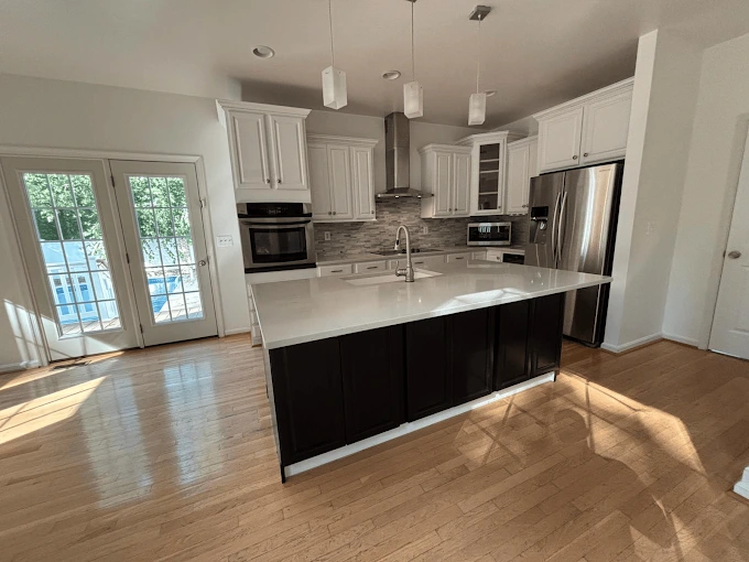 A sparkling modern kitchen with a large island and hardwood floors, highlighting the professional kitchen cleaning service by Brighthouse Cleaners.