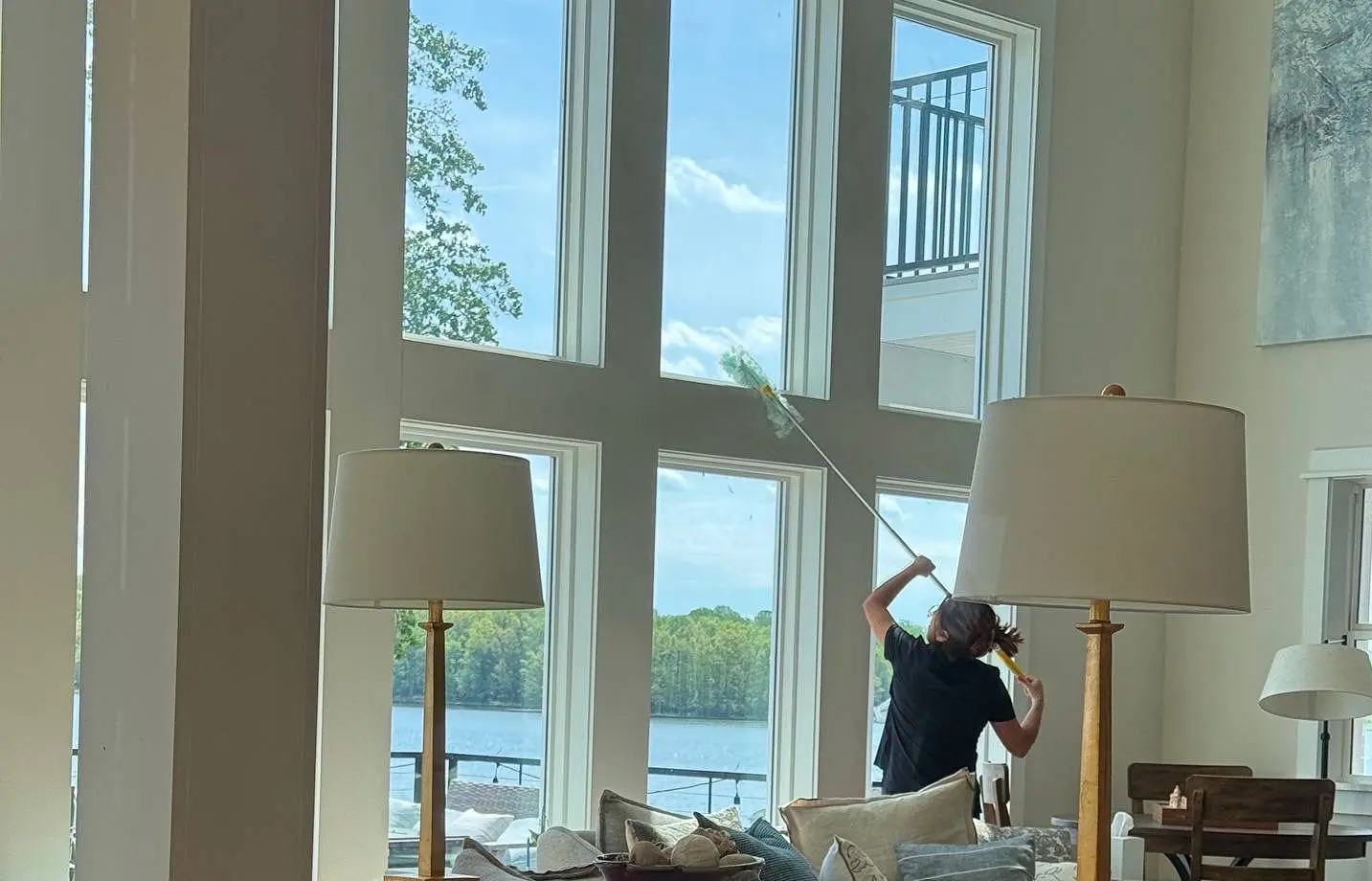 A Brighthouse Cleaners professional meticulously cleaning large windows, providing an excellent window cleaning service with a scenic outdoor view.